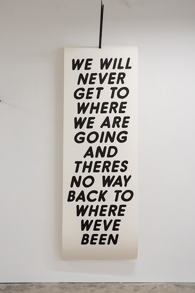 black and white text artwork hung on a white wall