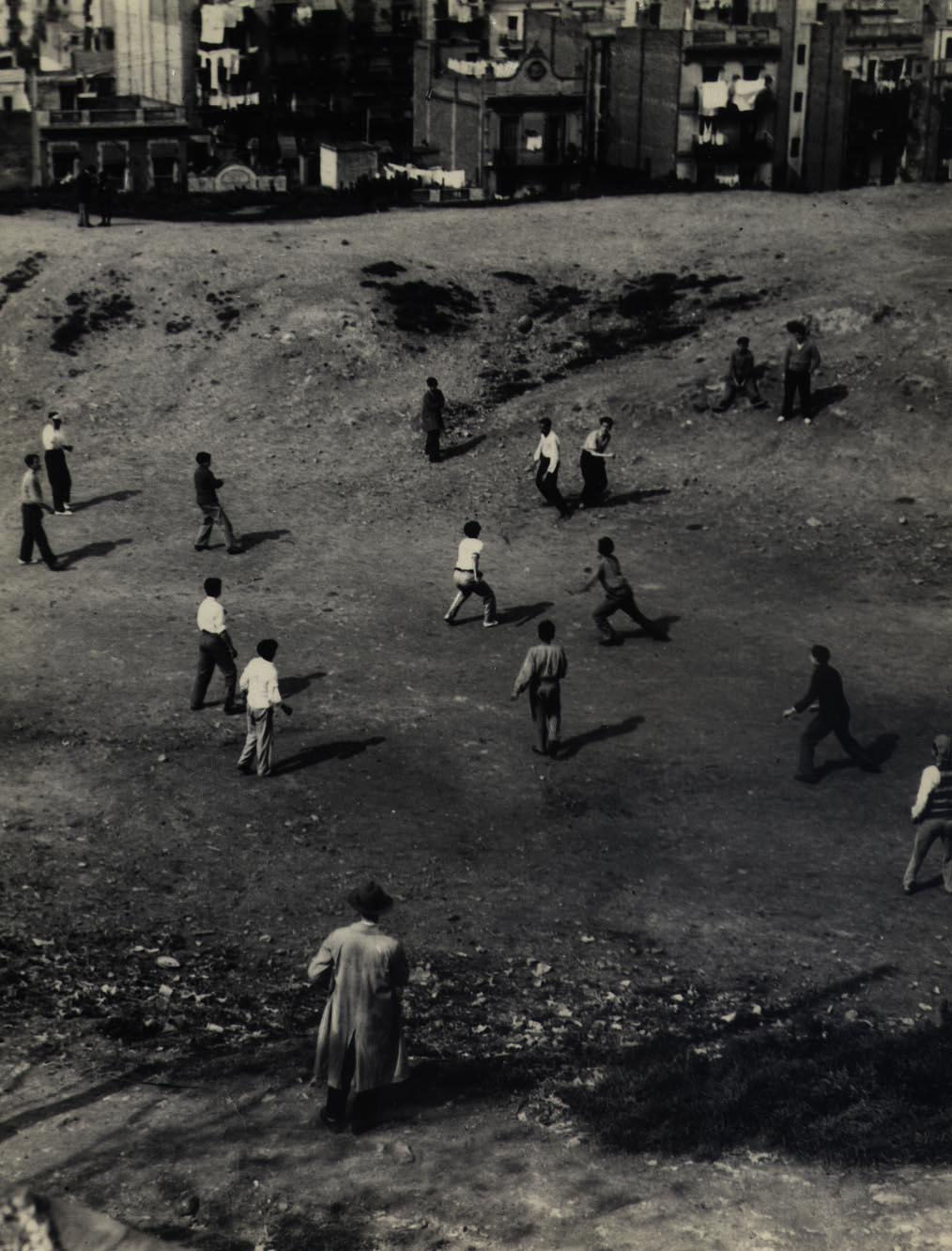 group of kids playing in dirt next to buildings in Barcelona