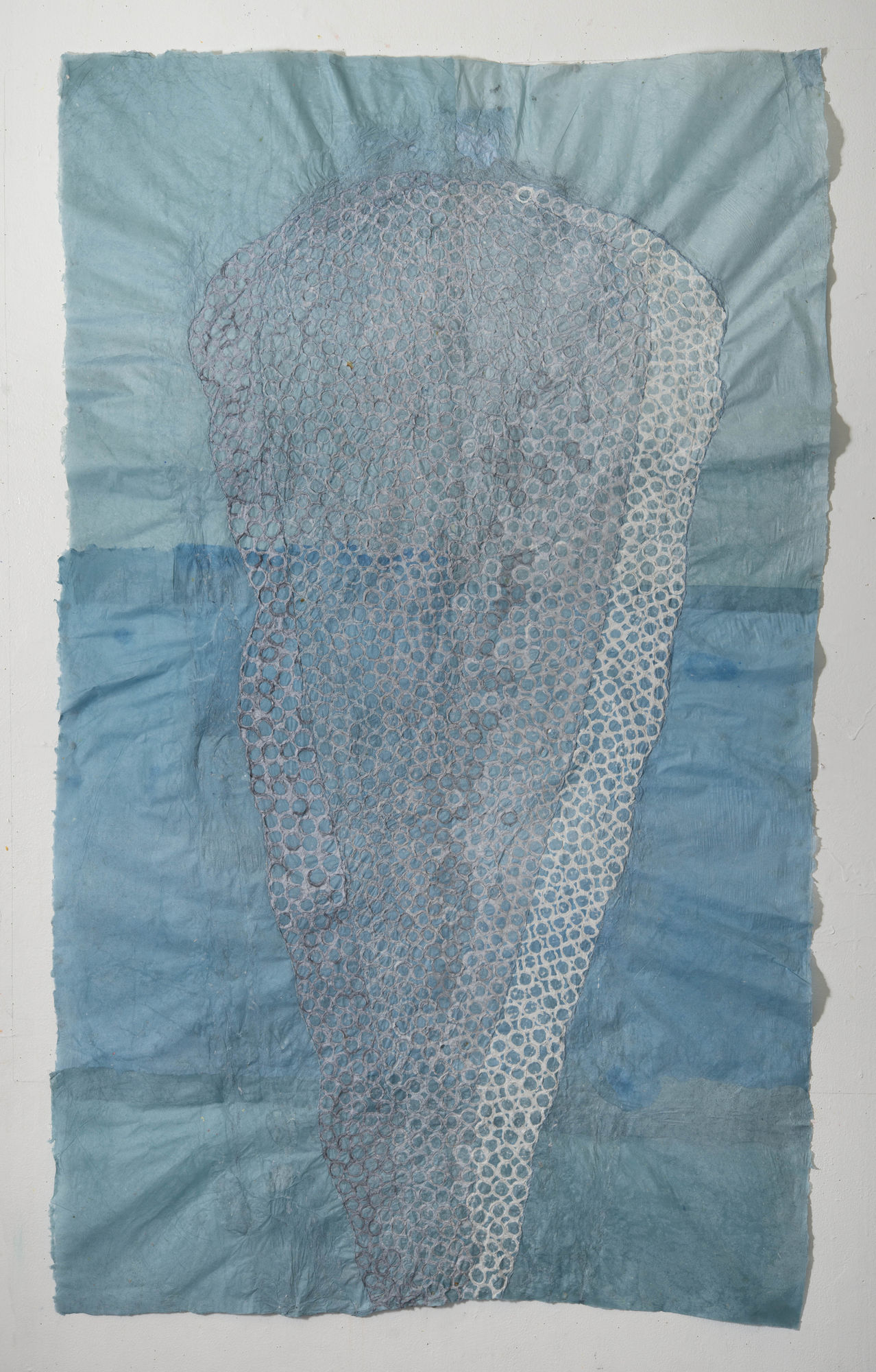 Nancy Cohen's "re: Precaurious" done with paper pulp and handmade paper in various shades of gray, white and blue. The piece depicts two layers of paper pulp the blue paper. These designs are overlapping each other creating depth.