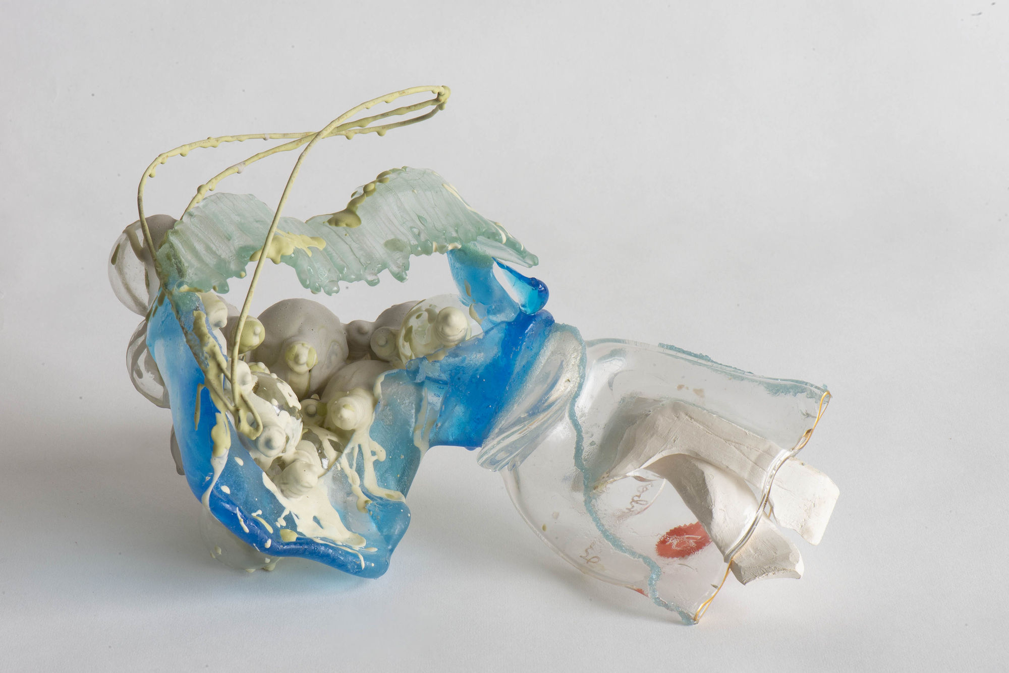 Nancy Cohen's "Fissure" art piece made from glass, wire, ceramic and aqua risen with blue, turquoise, white, and yellow color. Pieces of ceramic are places around the glass shards that are attached together.