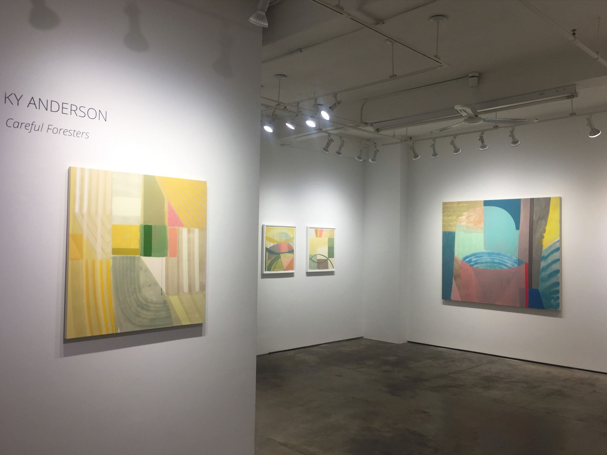 Installation shot of four abstract paintings by Ky Anderson. The painting close by the left is under wall lettering reading, "KY ANDERSON - Careful Foresters"
