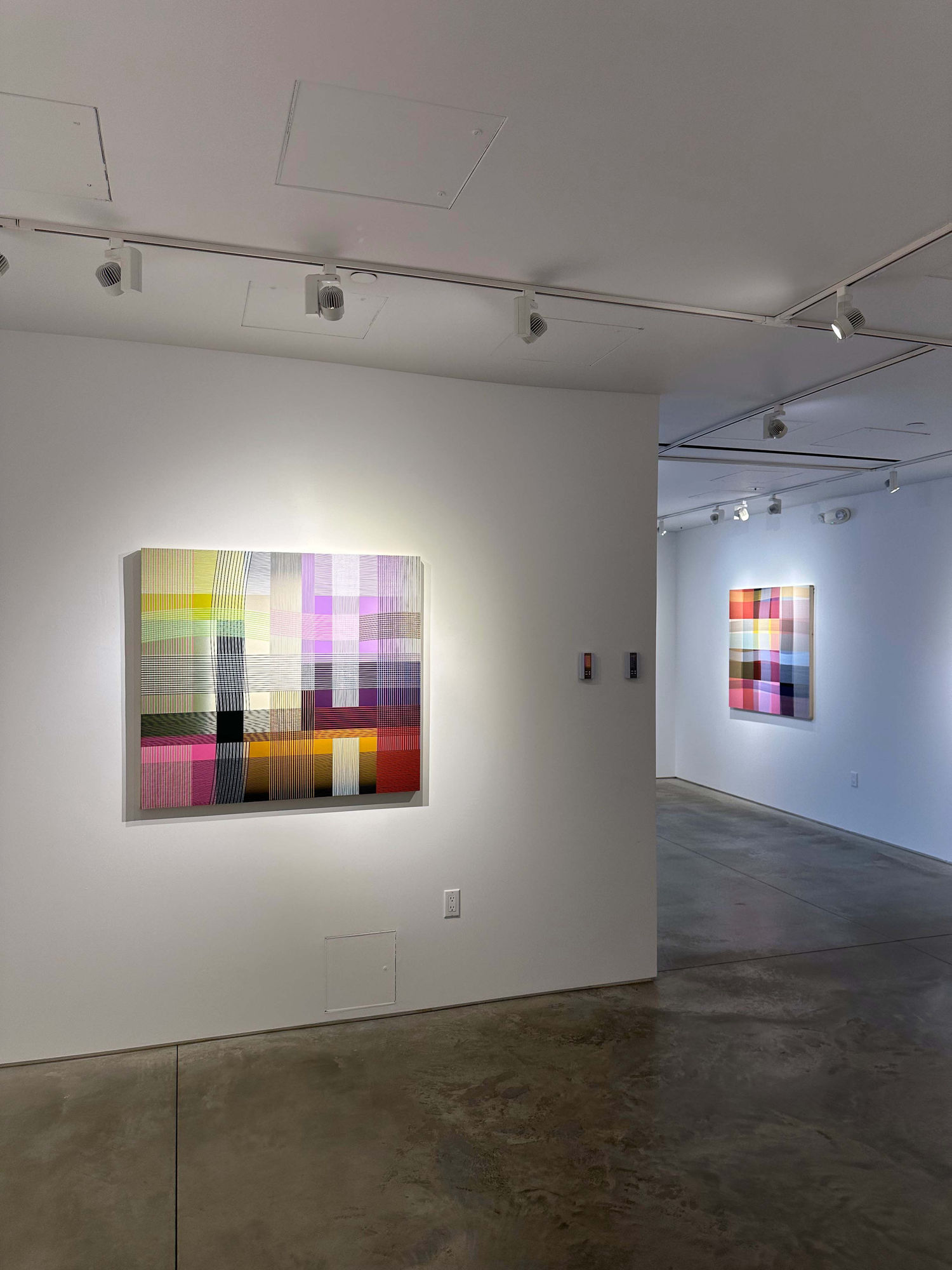 photo of an installation with two abstract paintings visible.