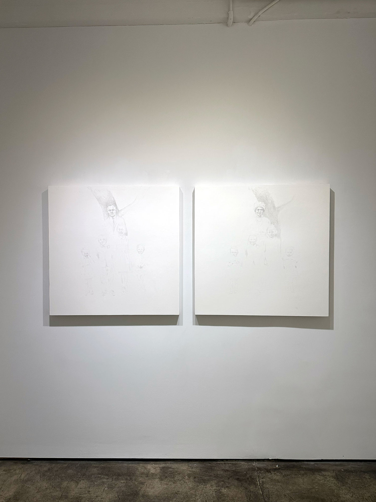 photo of an installation, with two primarily white paintings next to each other on the wall.