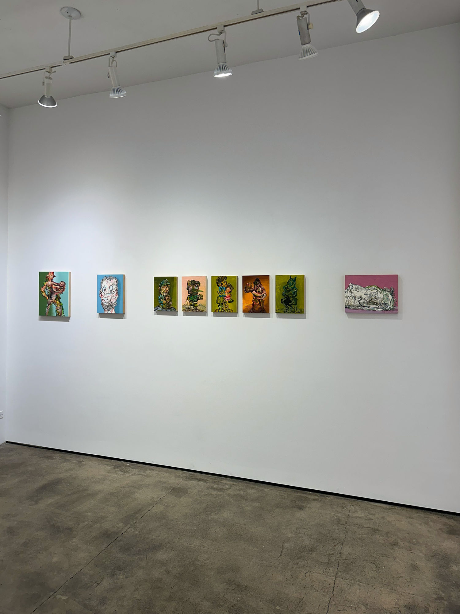 photo of an installation with 8 small paintings placed next to each other on the wall. They are not all the same size, but 5, in the middle, are.