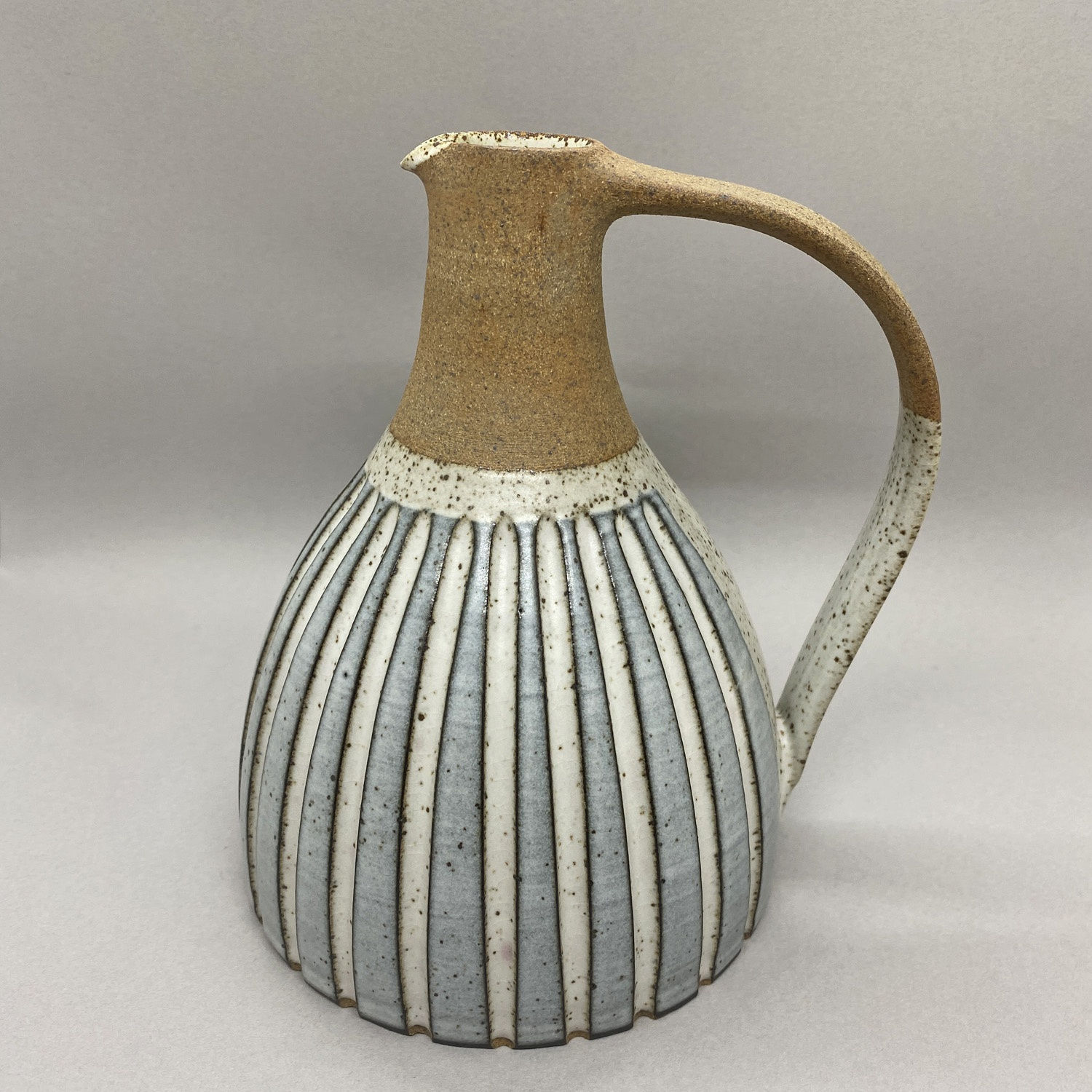 Kate Garwood jug in a round shape with a tall neck, a blue body with vertical white stripes.