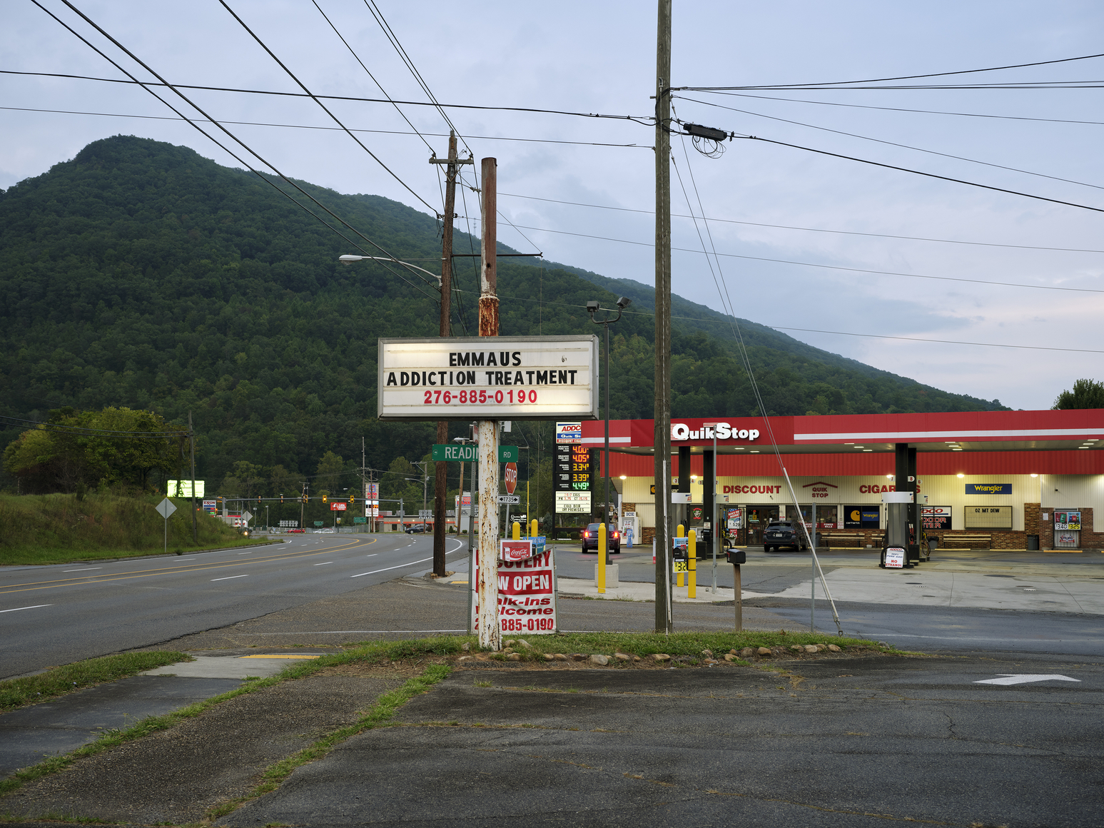 mountain landscape with a gas station whose sign reads "Emmaus Addiction Treatment"