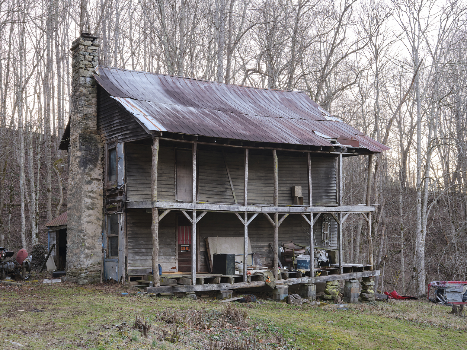 dilapidated log cabin house with keep out sign