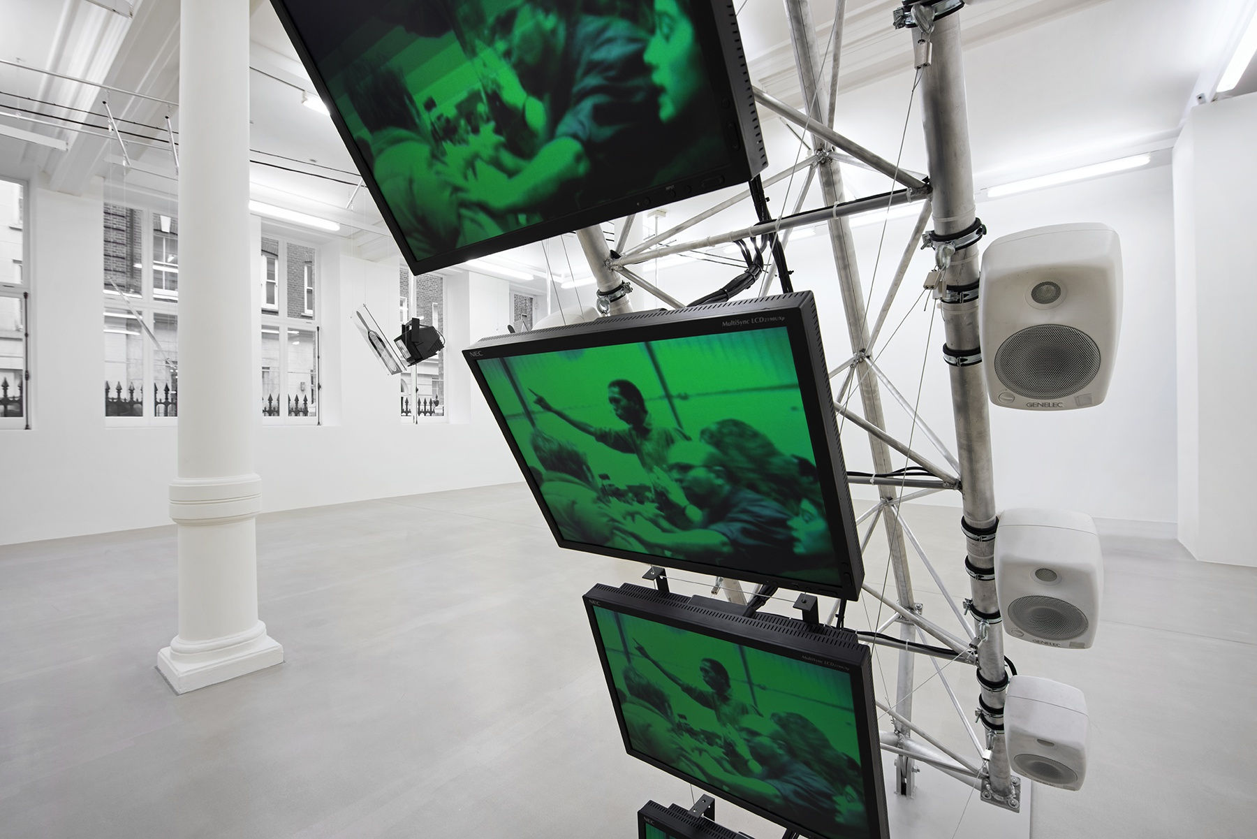 A close-up of 3 monitors stacked vertically displaying a green image of a crowd.