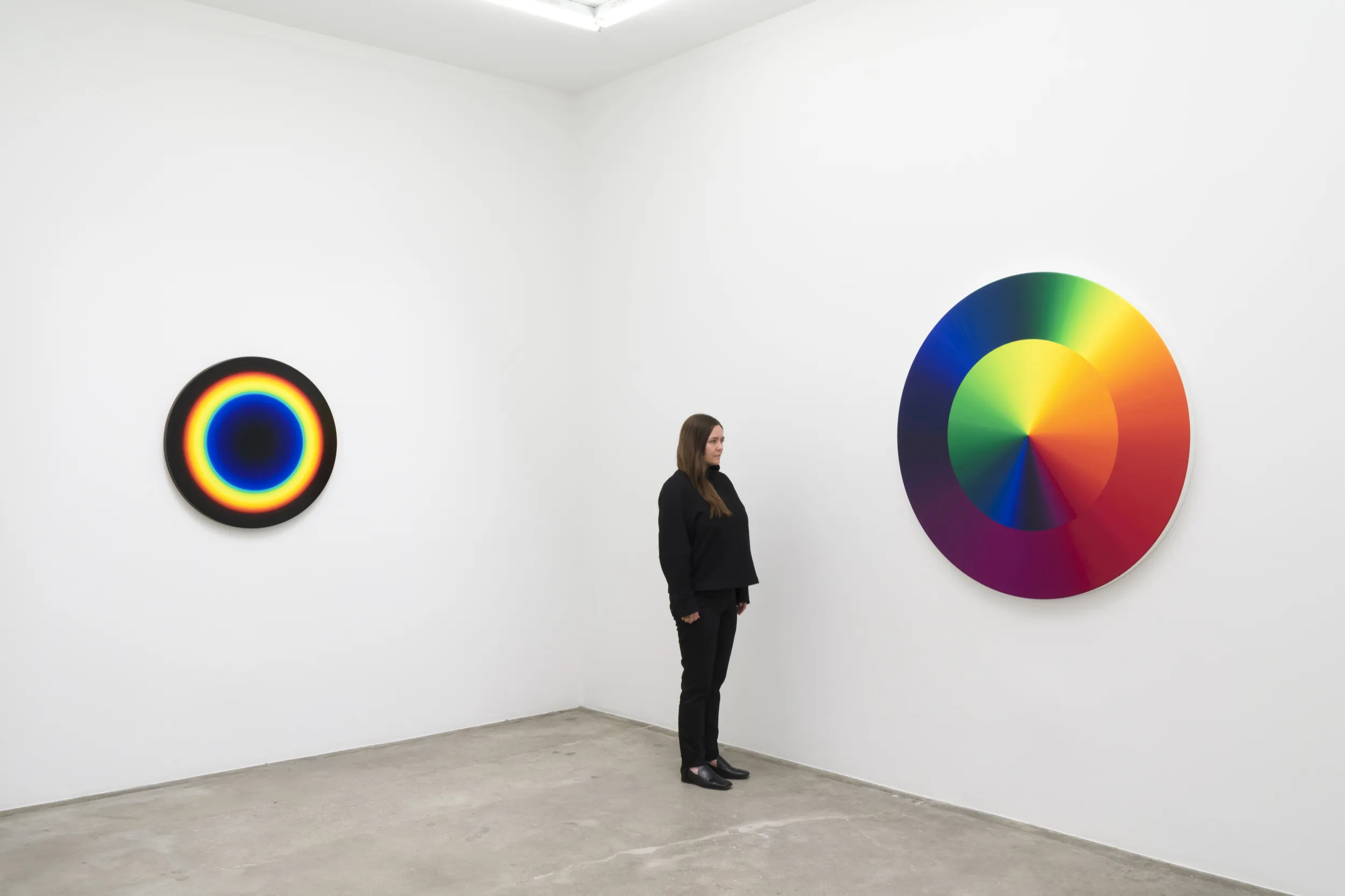 Installation view of two Olafur Eliasson circular paintings with a person