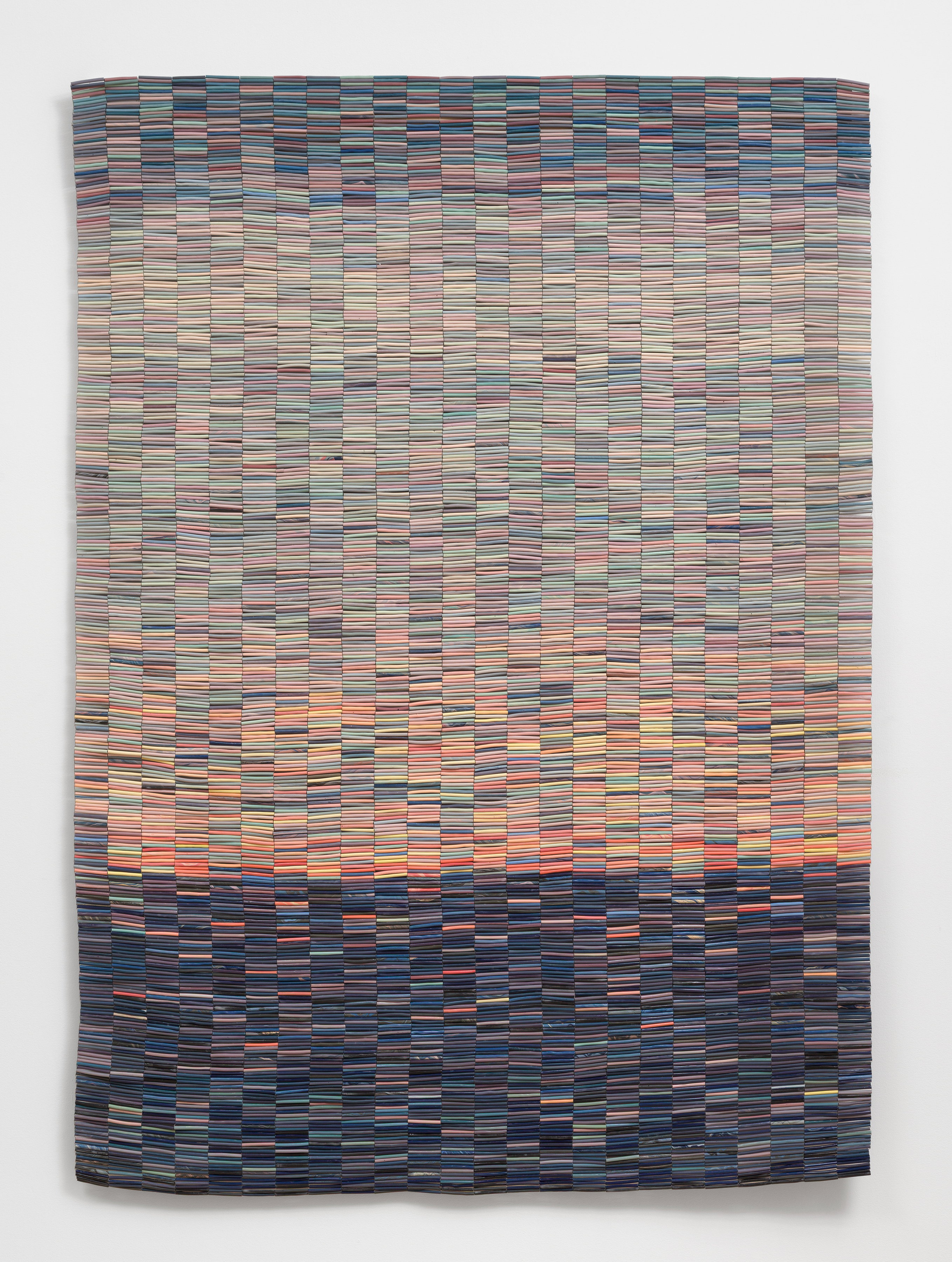 An artwork by Nadia Myre of ceramic tubular beads strung together into a cohesive rectangular with dark blue beads at the bottom and lighter orange, yellow and blue beads above.