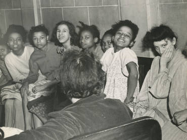 Several children look towards the camera in this black and white photo, some of the children are smiling