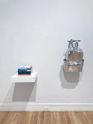 Reflective kids backpack filled with "queer secrets" hangs alongside a stack of banned LGBTQ books