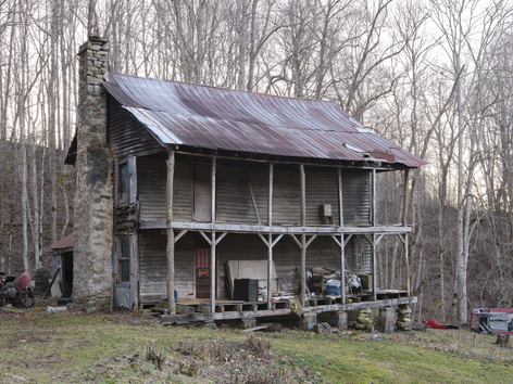 dilapidated log cabin house with keep out sign