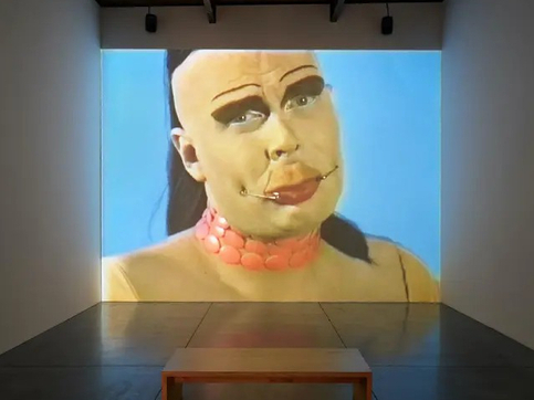 Video projection in a darkened art gallery - Leigh Bowery against a light blue background