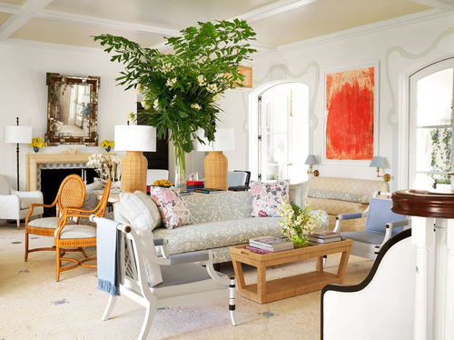 A bright Christopher Le Brun painting overlooks a salon in shades of stone, sky blue, and coral, featuring 1970s Spanish rattan chairs, vintage lamps, a Casa Branca Brighton sofa, and a pair of 1950s Maison Jansen white lacquered fauteuils. Simon Upton