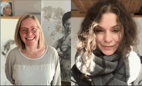 Two smiling women posing indoors with artwork in the background.