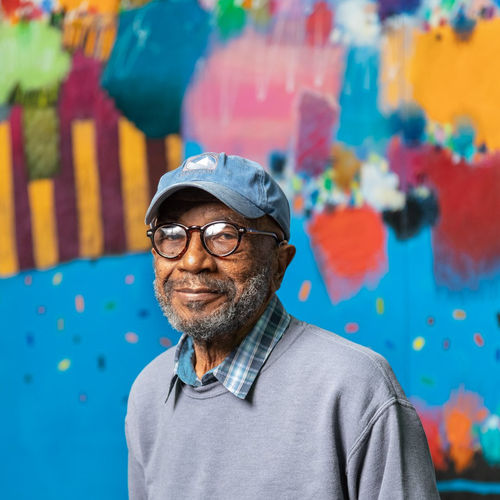 Photo of Moe Brooker in front of his mural, The Fruit of the Spirit, 2018-2020