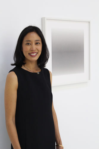 Nicole Phungrasamee Fein stands in front of one of her framed paintings on paper