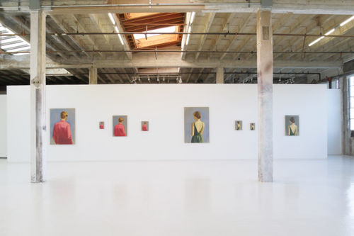 A wall with eight paintings, four of a man from behind in a red shirt, and four of a woman from behind in a green dress.