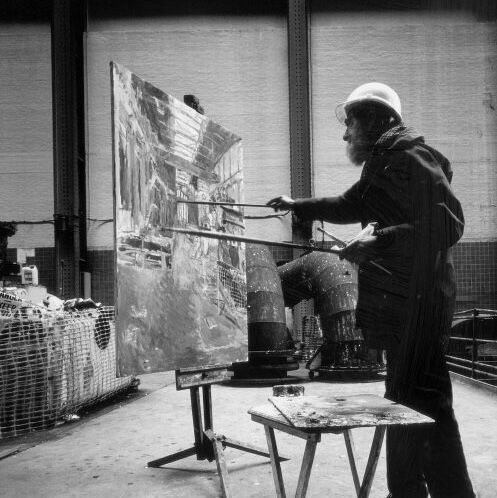 Black and white photograph of artist Anthony Eyton painting in his studio