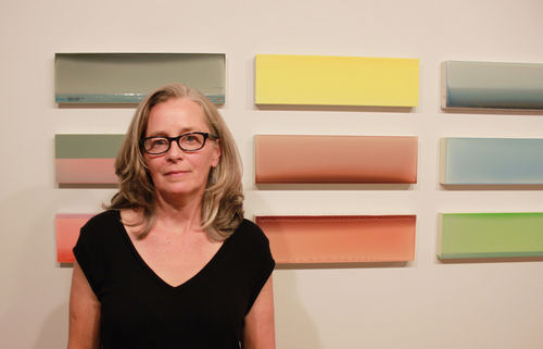 Susan English standing in front of several of her paintings.