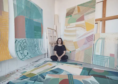 Ky Anderson sitting in her studio amidst paintings.