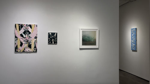 Paintings and a pastel hanging on a gallery wall.