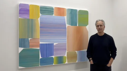 Erick Johnson standing with his painting "Sanctum."