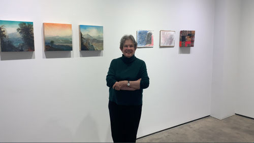 Woman standing in front of six small artworks.