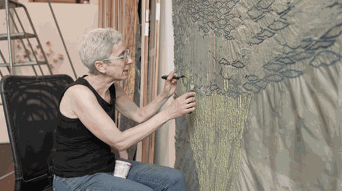 Woman artist working on a large-scale handmade paper piece of art.