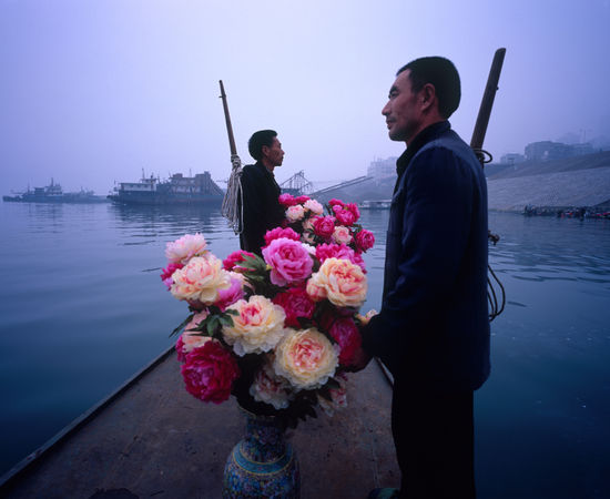 Two Bang Bang men and two vases of flowers are on the boat.