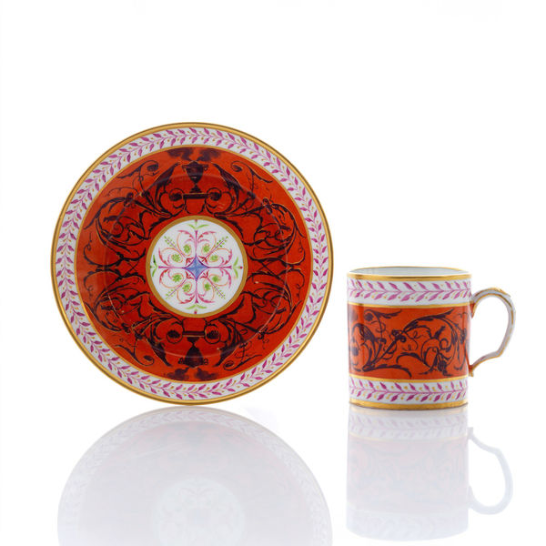 Sèvres Porcelain, A Hard-Paste Sèvres Porcelain Cup & Saucer with Dark Arabesques on a Terracotta Ground, 1785