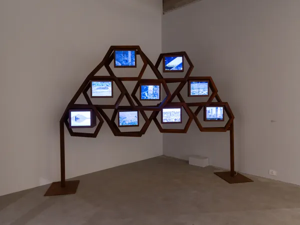 Gigi Scaria Territories in transit , 2026 MS pipes, monitors (9), videos, video spliter and speaker 304.8 x 228.6 x 116.8 cm 120 x 90 x 46 in