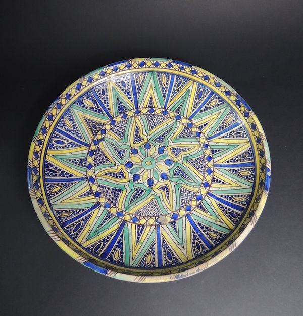 large terracotta plate on ring-foot, decorated by floral and abstract patterns