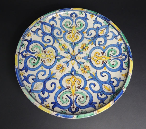 Terracotta plate on ring-foot decorated by floral patterns in blue, green and yellow