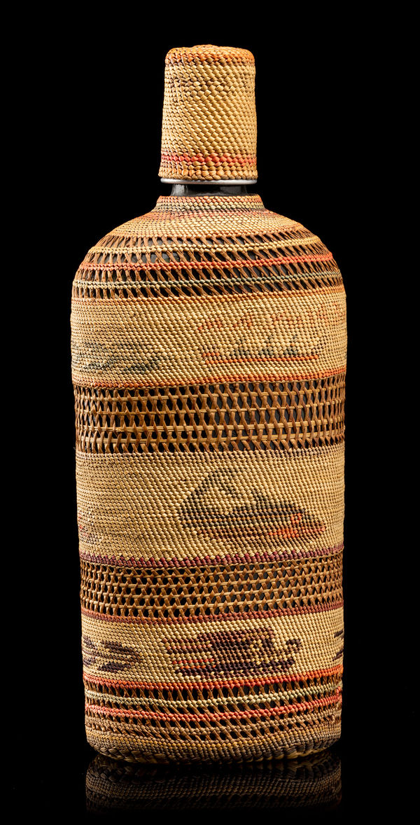Lot 114 UNIDENTIFIED NUU-CHAH-NULTH ARTIST Basketry Woven Macallan Whisky Bottle, c. 1920 glass bottle, tin cap, natural and dyed grass, and cedar bark, 10.25 x 4.25 x 2.75 in (26 x 10.8 x 7 cm) ESTIMATE: $1,200 — $1,800 PRICE REALIZED: $1,159.00