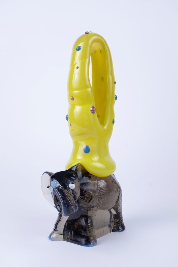 Rasmus Nossbring glasskulptur med grå elefant med utåtstående ögon med en gul ovan med prickar på.