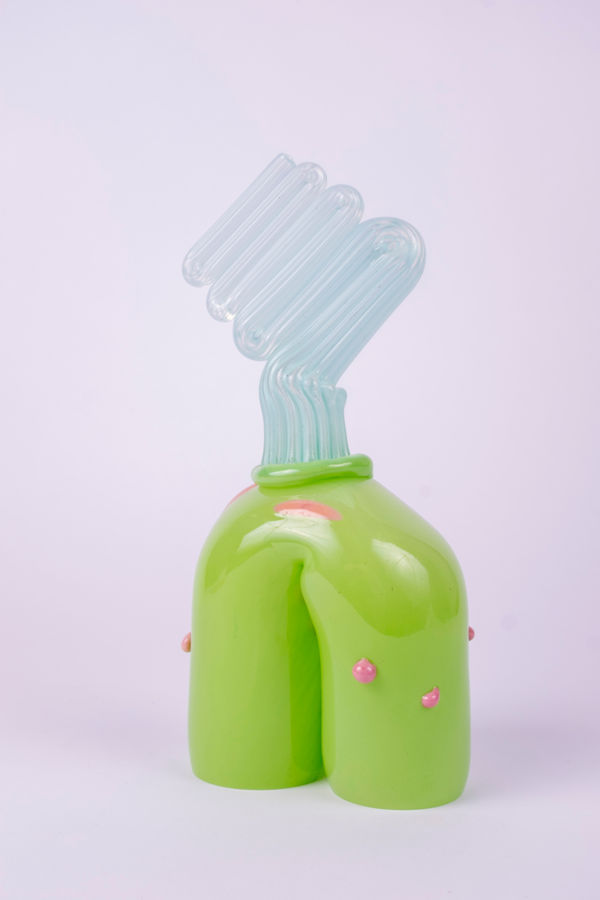 Rasmus Nossbring glasskulptur i ljusbår kaviarstäng ovanpå en grön böj med rosa prickar.