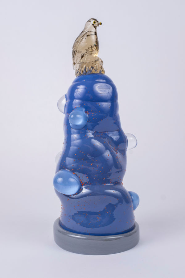 Rasmus Nossbring glasskulptur med brun fågel sittande på ett blått glasberg med bubblor.