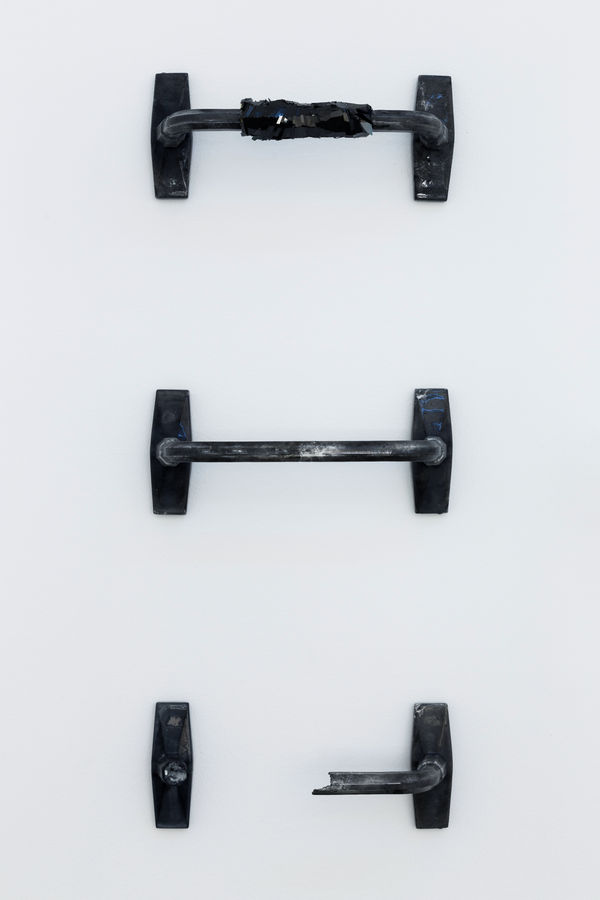 An image of three dumbbell shaped silicone rubber objects against a white wall.