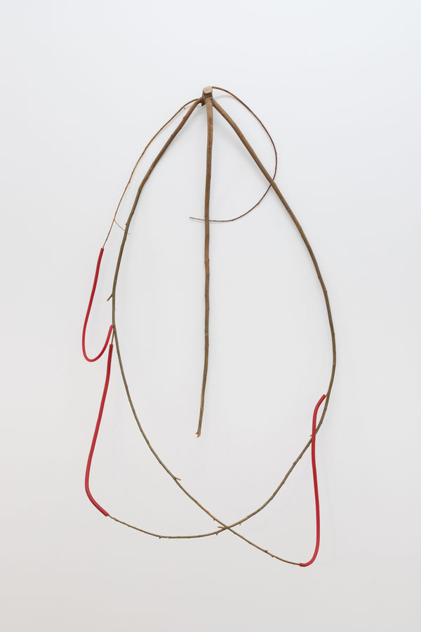 a spindly wall-mounted sculpture made of wood and wax