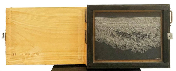 White drawing on black paper in a wooden box