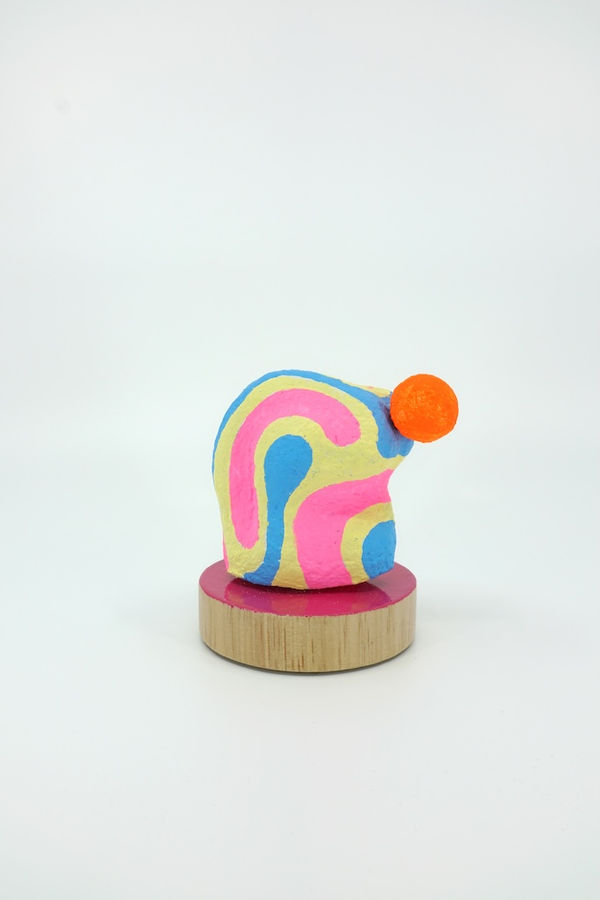 Pink, blue, and yellow shaped sculpture on a pink wooden circle