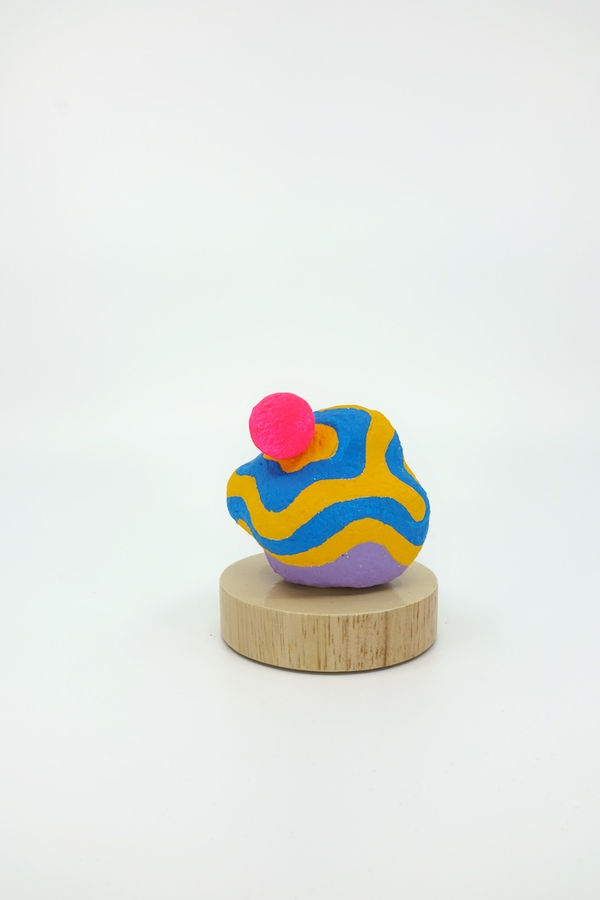 Blue and orange sculpture with a bright pink sphere on top of it