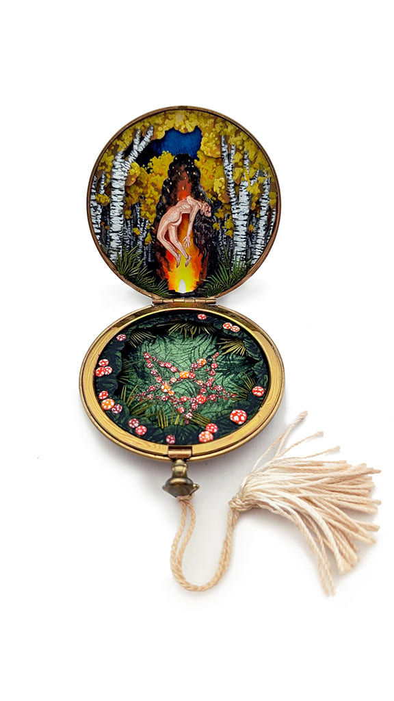 hand-cut watercolor collage in antique cosmetic compact by Shannon Taylor with a naked woman hovering over a large fire in the woods