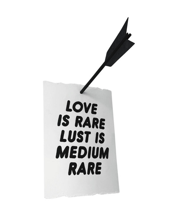 Piece of paper with the words "LOVE IS RARE LUST IS MEDIUM RARE" on it and an arrow going through it