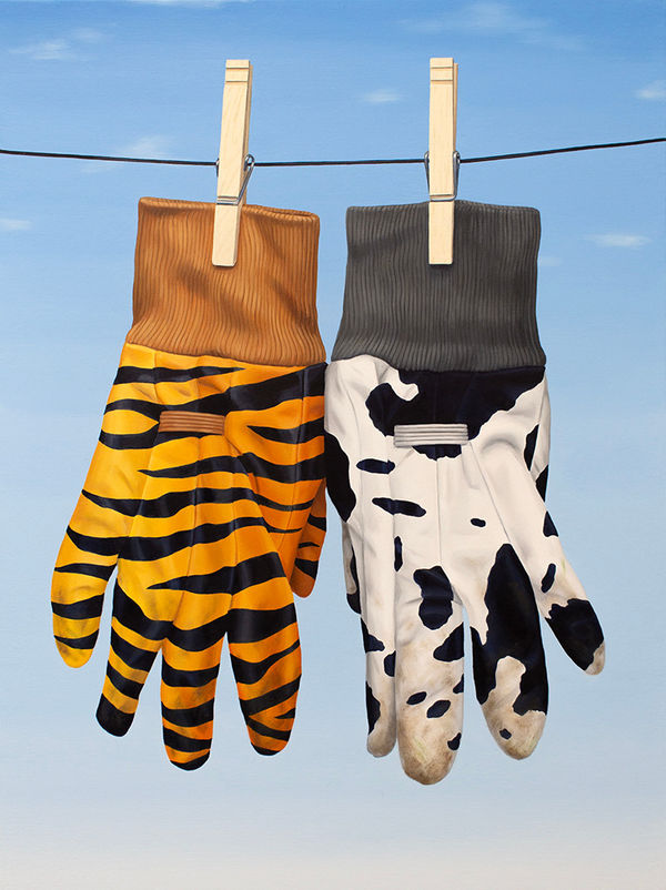 Two gloves hanging on the clothes line, one with a cow print and the other with Tiger print