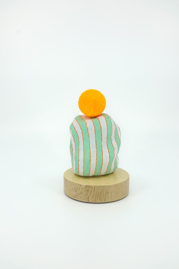 White and green striped sculpture with a yellow sphere on top of it
