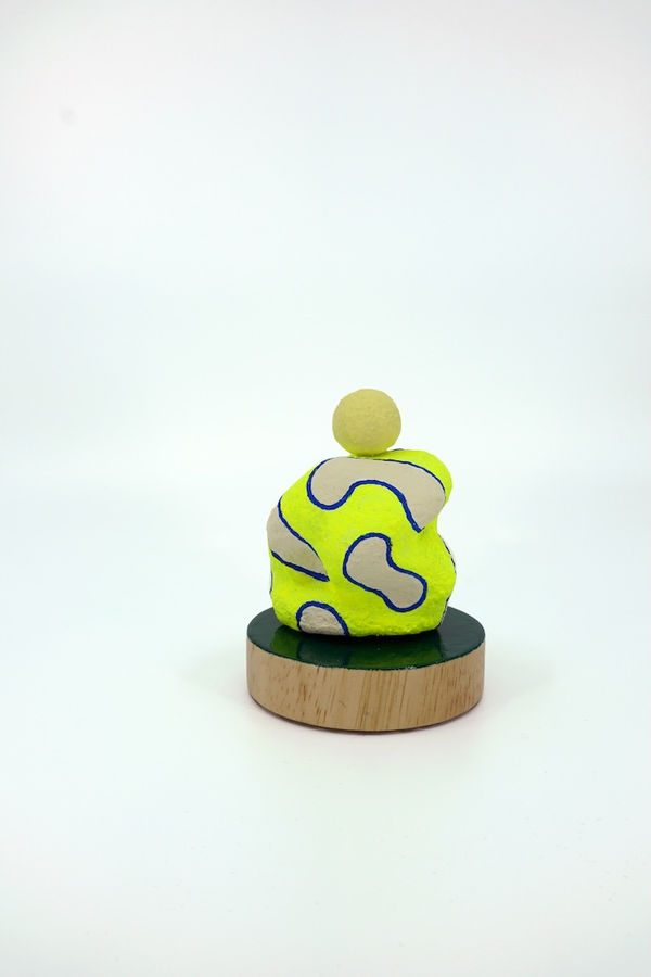 Neon yellow blob shaped sculpture with a yellow sphere on the top of it
