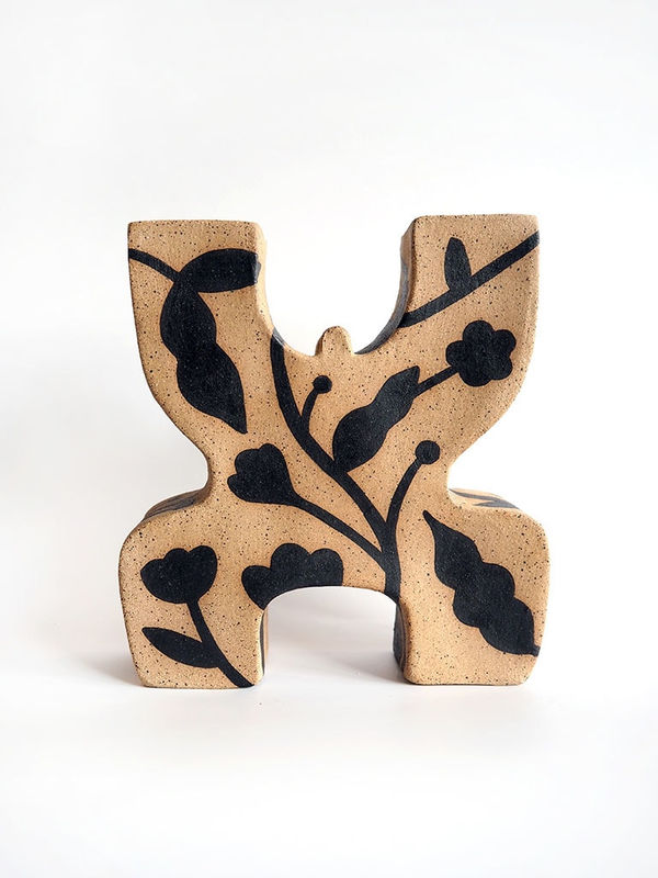 ceramic figure by Jocelyn Tsaih of a brown figure with black flowers on it
